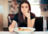 Food Allergies That Can Kill Woman covering mouth while looking at a plate of pasta