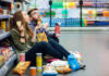 Conquering Food Cravings – How Restriction Backfires A young couple sitting on the floor of a grocery store enjoying snacks