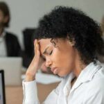 How Long Your Brain Takes To Recover From Stress Woman in office holding her head with eyes closed