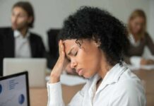 Nationwide Fatigue Spike Tied To Anxiety Woman in office holding her head with eyes closed