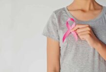 Pink Ribbons Don’t Save Lives Person holding a pink ribbon on a gray shirt