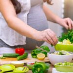 Person preparing a fresh salad with green vegetables in a kitchen