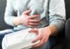 Packaged Food Tied To Artery Damage Person holding stomach with takeout container on lap