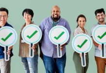 Group of five people holding large checkmark signs