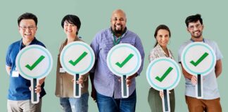 Group of five people holding large checkmark signs
