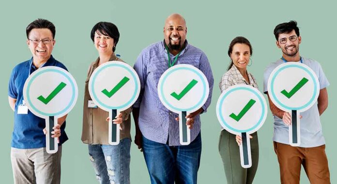 Group of five people holding large checkmark signs