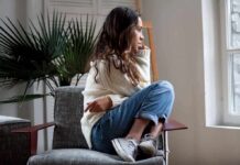 Woman sitting curled up on a chair looking out a window