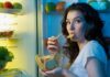 Woman snacking at an open refrigerator