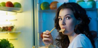 Woman snacking at an open refrigerator