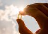 Hand holding a translucent capsule against bright sunlight