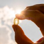 Hand holding a translucent capsule against bright sunlight