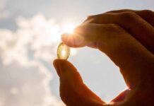 Hand holding a translucent capsule against bright sunlight