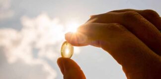 Hand holding a translucent capsule against bright sunlight