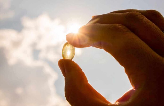 Hand holding a translucent capsule against bright sunlight