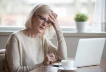 Signs Your Forgetfulness Could Be Something More Serious Older woman with glasses looking concerned at laptop