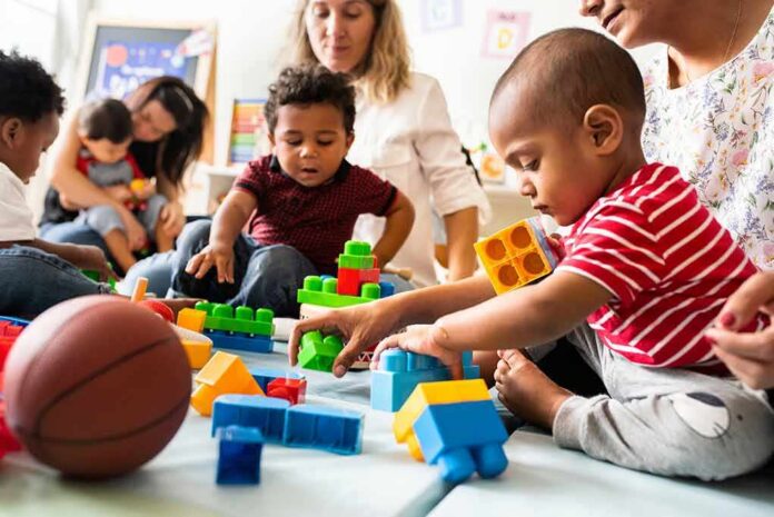 Karyn Polito with toddlers building blocks on a play mat
