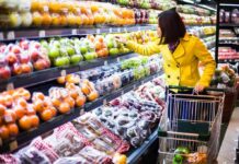 Woman in a yellow coat shopping for fruits in a supermarket