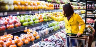 Woman in a yellow coat shopping for fruits in a supermarket
