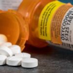 white pills spilling from prescription bottles