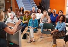 Why Asking For Help Builds Strength Instead Of Weakness Audience listening to a speaker in a small community meeting room