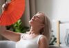 Using GLP-1s During Menopause: What Women Need to Know Woman fanning herself with an orange hand fan