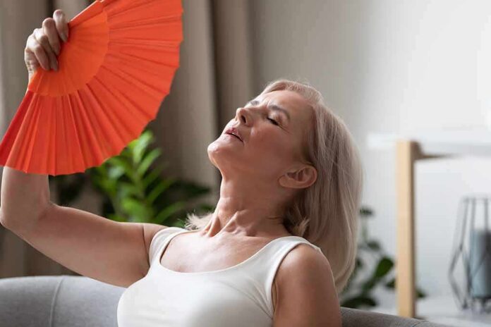 shutterstock_1504807925 Woman fanning herself with an orange hand fan