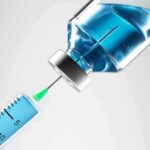Syringe drawing blue liquid from vial