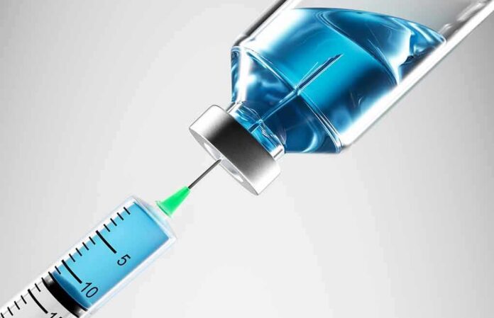 Syringe drawing blue liquid from vial