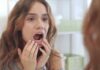 Flossing Tricks for Permanent Retainers and Braces young woman checking inside her mouth in bathroom mirror