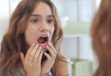 Flossing Tricks for Permanent Retainers and Braces young woman checking inside her mouth in bathroom mirror