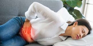 Woman lying on couch holding her lower abdomen in pain