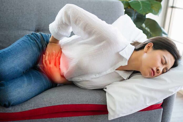 Woman lying on couch holding her lower abdomen in pain