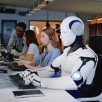 AI’s Compassion Illusion Exposed Robot and office workers at computers in a modern workspace