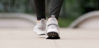 Close-up of person walking in gray sneakers