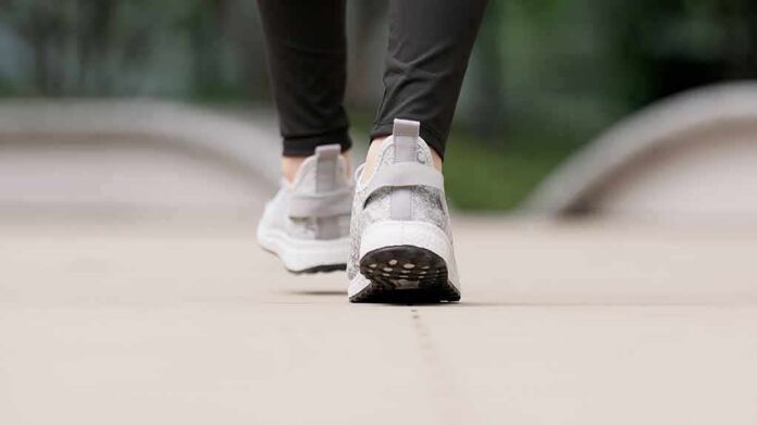 shutterstock_2573903849 Close-up of person walking in gray sneakers