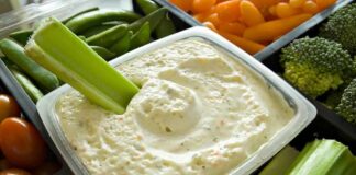 Celery dipped in creamy vegetable dip in a tray of fresh veggies