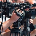 Grandma’s Tile Game Outsmarts Brain Apps television cameras on tripods at a media event