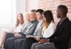 Job applicants seated in a row with clipboards