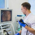 Doctor holding endoscope beside monitor during procedure