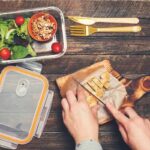 Hands slicing cooked chicken on a wooden cutting board
