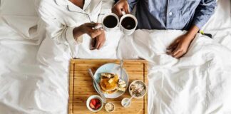 Breakfast in bed with two people holding coffee