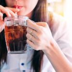 Beer And Soda Linked To Gout Spike person sipping iced drink from a glass mug with a straw