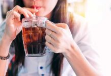 Beer And Soda Linked To Gout Spike person sipping iced drink from a glass mug with a straw
