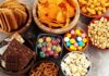Assorted snacks in bowls including chips, candies, nuts, popcorn, and chocolate