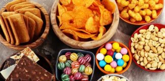 Assorted snacks in bowls including chips, candies, nuts, popcorn, and chocolate