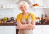 Smiling older woman in apron standing in a bright kitchen