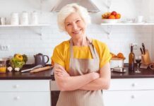 Fish, Walk, Feast – The Survival Blueprint Smiling older woman in apron standing in a bright kitchen