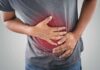 Mailed Poop Test Slashes Colon Cancer Deaths Person clutching stomach with colon illustration overlay