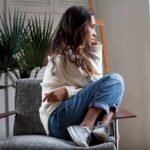 Woman sitting curled up on a chair looking out a window