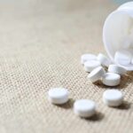 Common Pill Upsets Cancer Playbook White tablets spilling from a plastic bottle